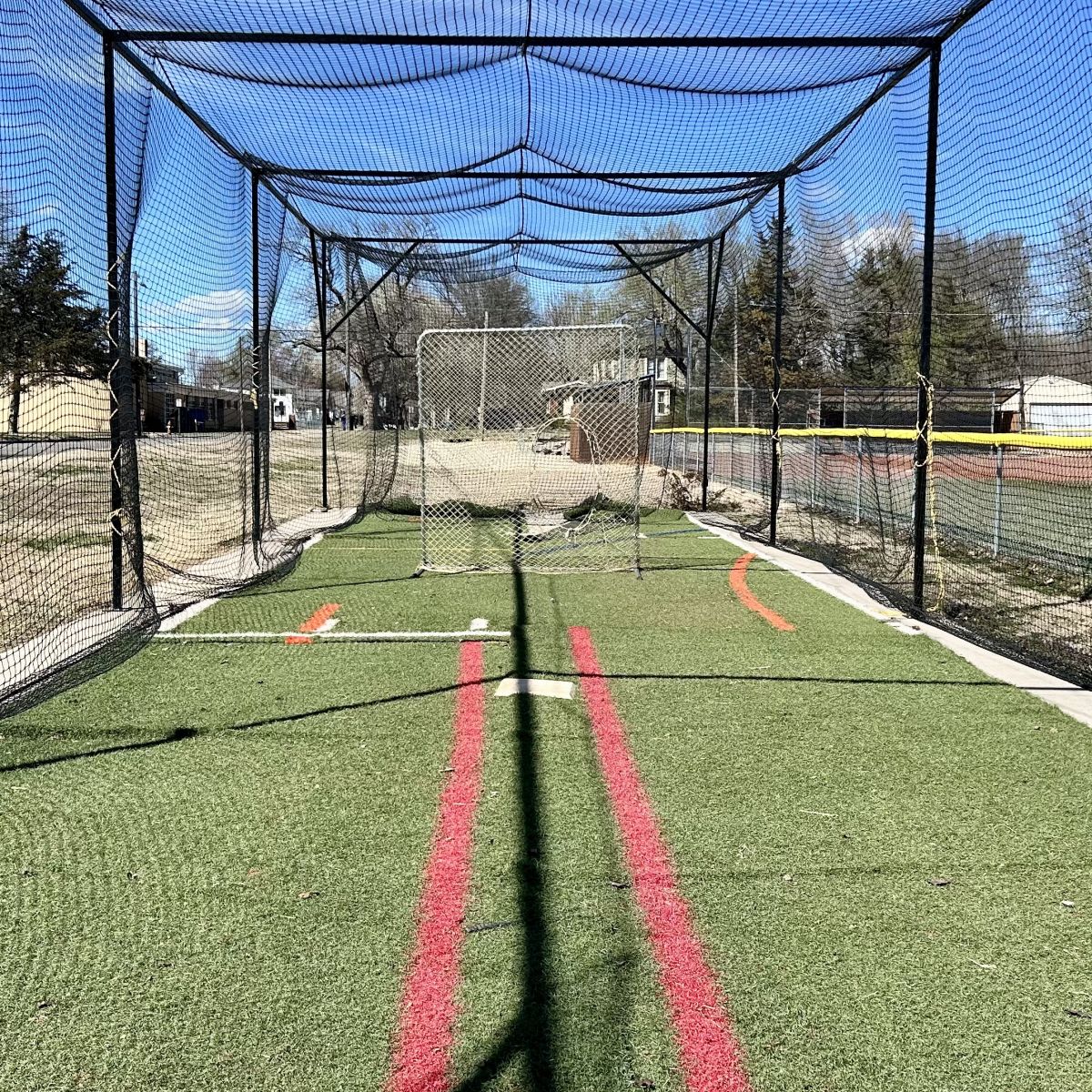 nets surrounding a fake grass area set up for practicing pitching and batting