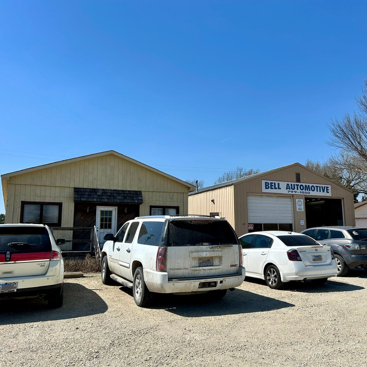 cars parked infront of 2 buildings that make up the Bell Automotive office and shop
