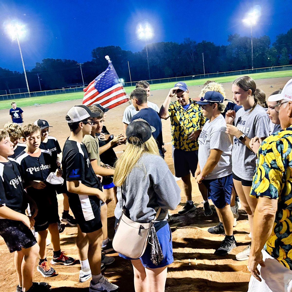 two teams gathered with an American flag in the background before the big game