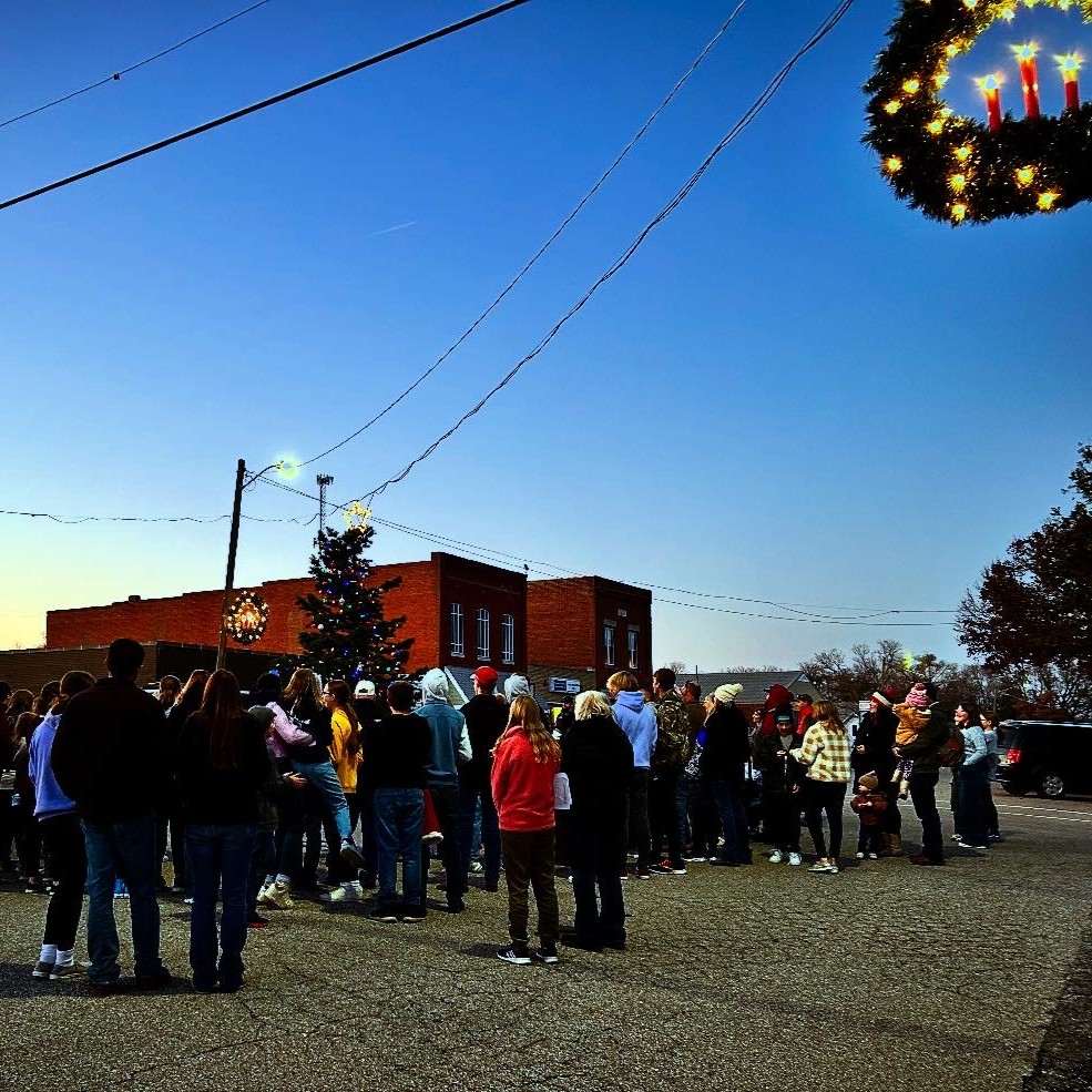Community gathered on main st around a christmas tree at sundown