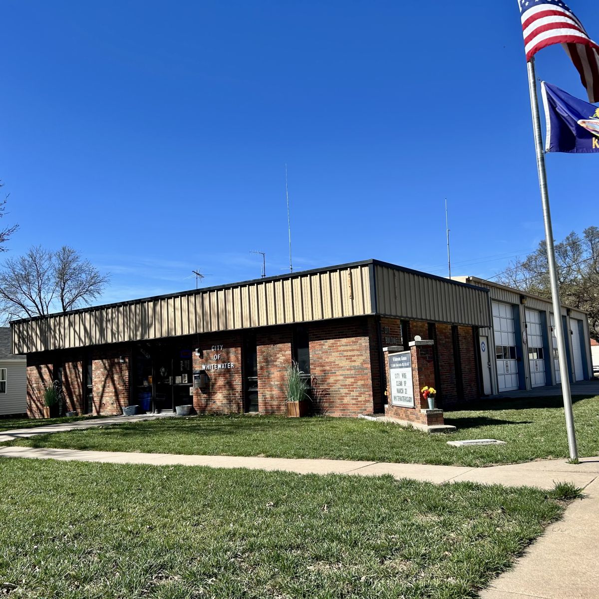 single story brick building with letter marquee on the corner, behind the front is the Fire Station housing trucks with multiple garage doors.