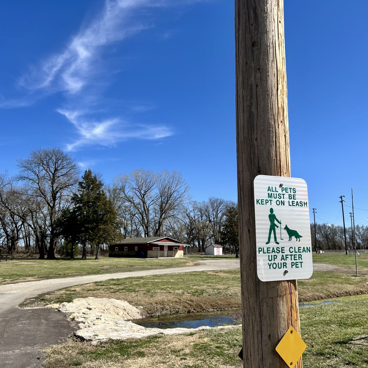 Sign posted out at parks saying dogs must be on a leash and pick up their poop