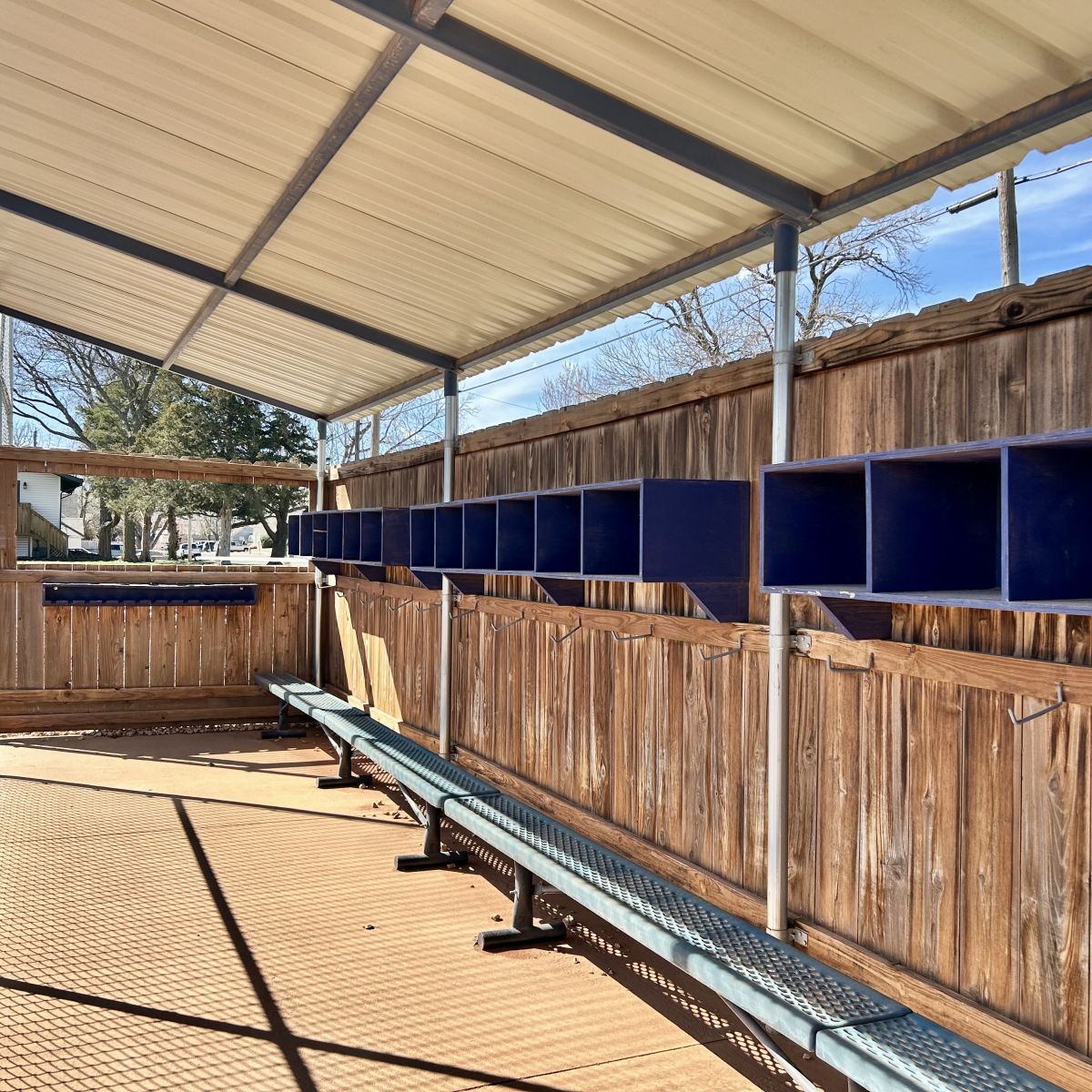 inside a dugout, wood surrounding with blue cubbies and blue shelves