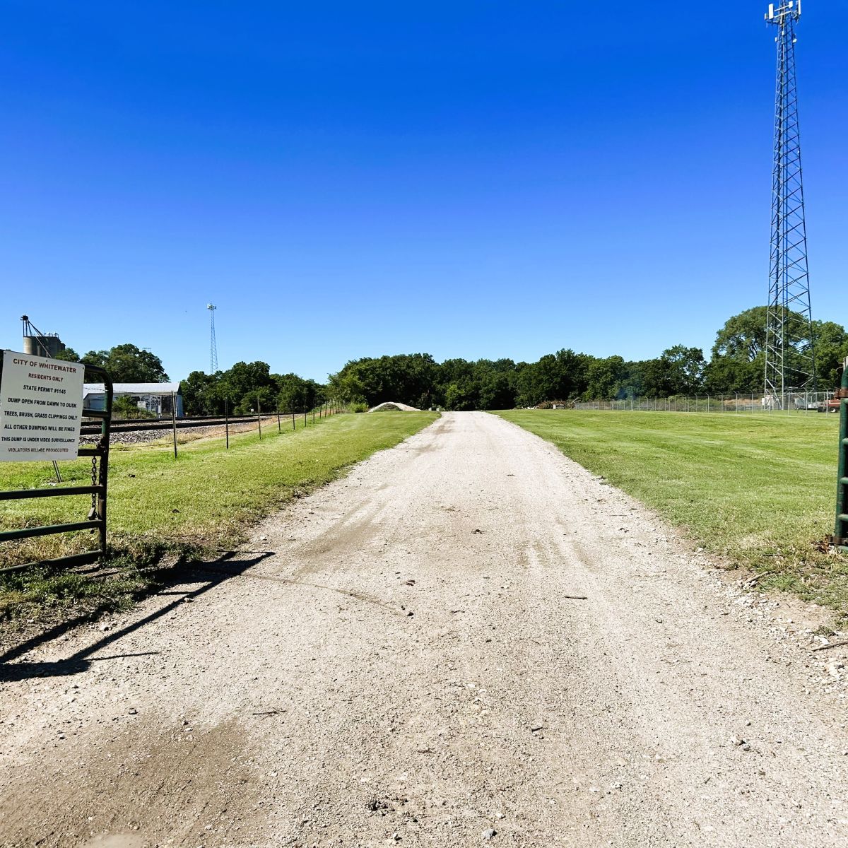 open gate with a dirt road leading to the city dump location