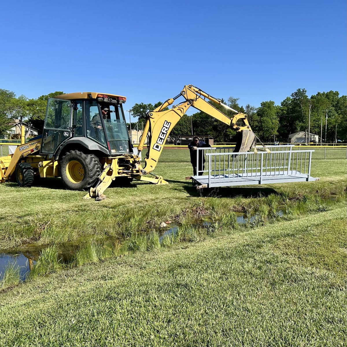 machinery moving a repurposed bridge to the ballfields