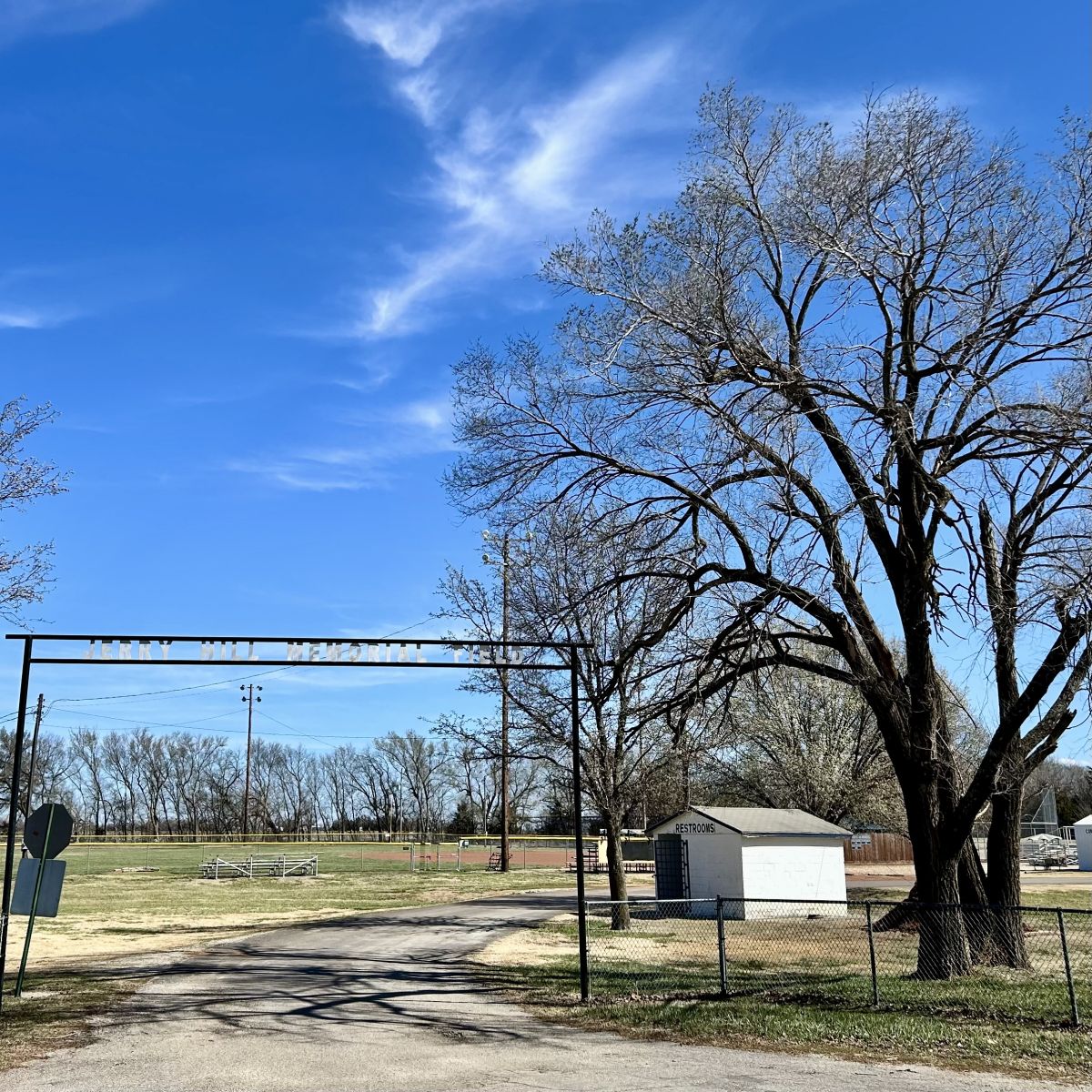 Fences lead up to a drive which is the entance for ballfield #1, has concession stand, bathrooms, bleachers and more
