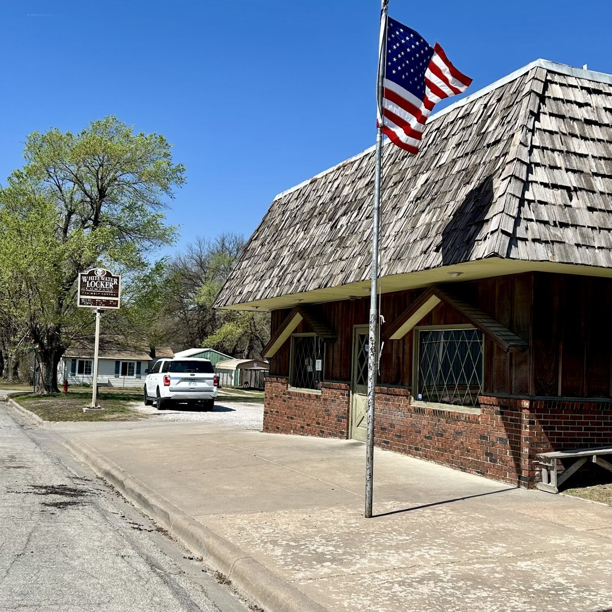 American Flag flying infront of a wooden structure that is the meat locker or butcher shop