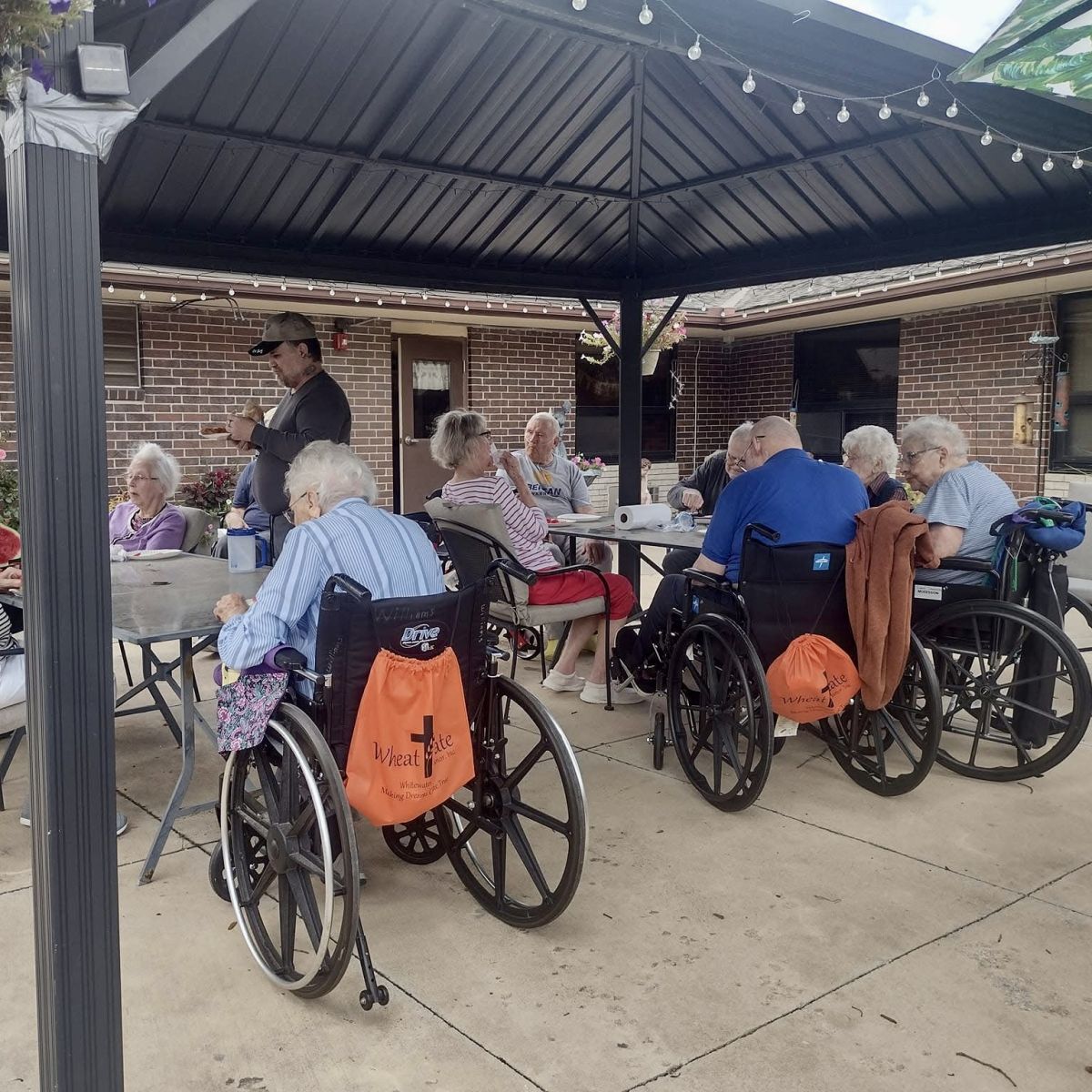 wheel chairs and individuals from the nursing home gathered under a covered patio