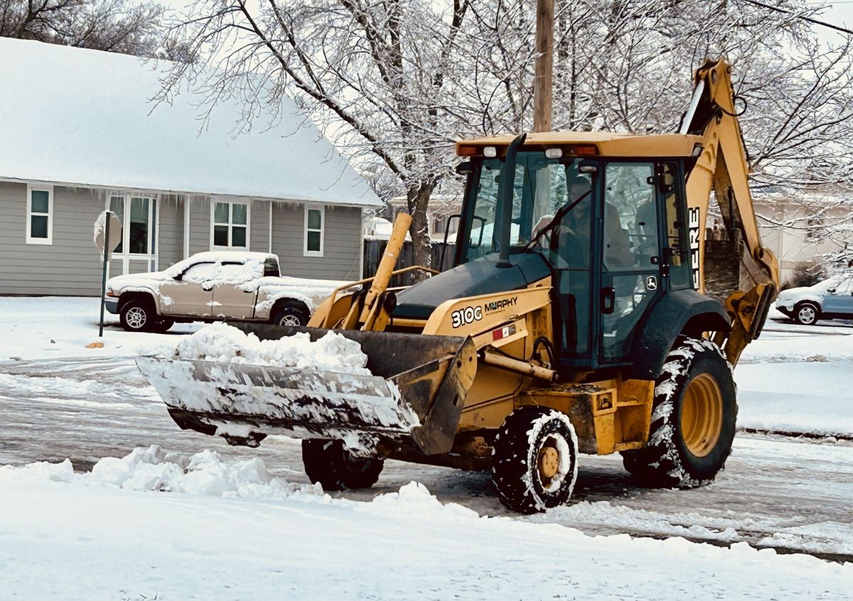 backhoe scooping snow to clear streets