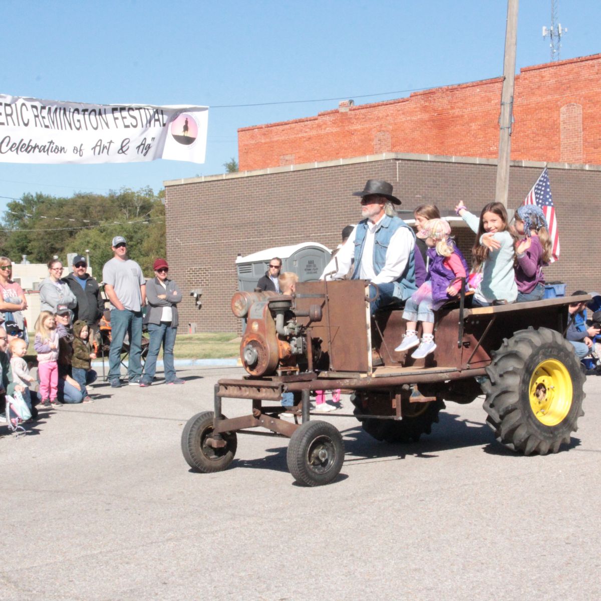 old tractor with kids throwing candy from the back in parade