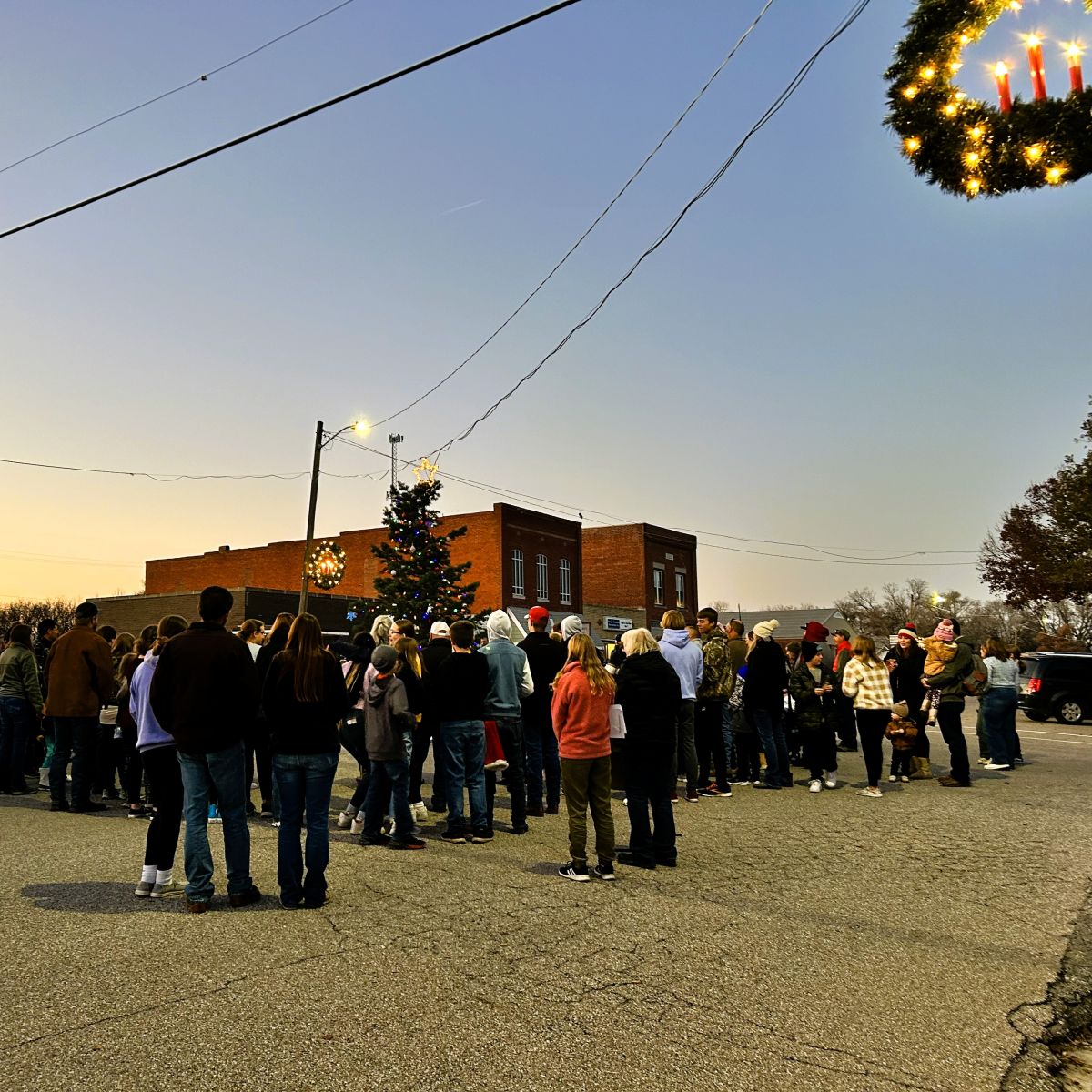 Many people gathered around a Christmas Tree in the middle of Main Street