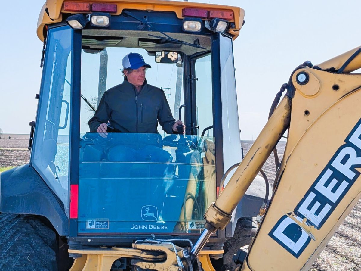 Andrew Hanna in the cab of a backhoe digging to repair a water leak