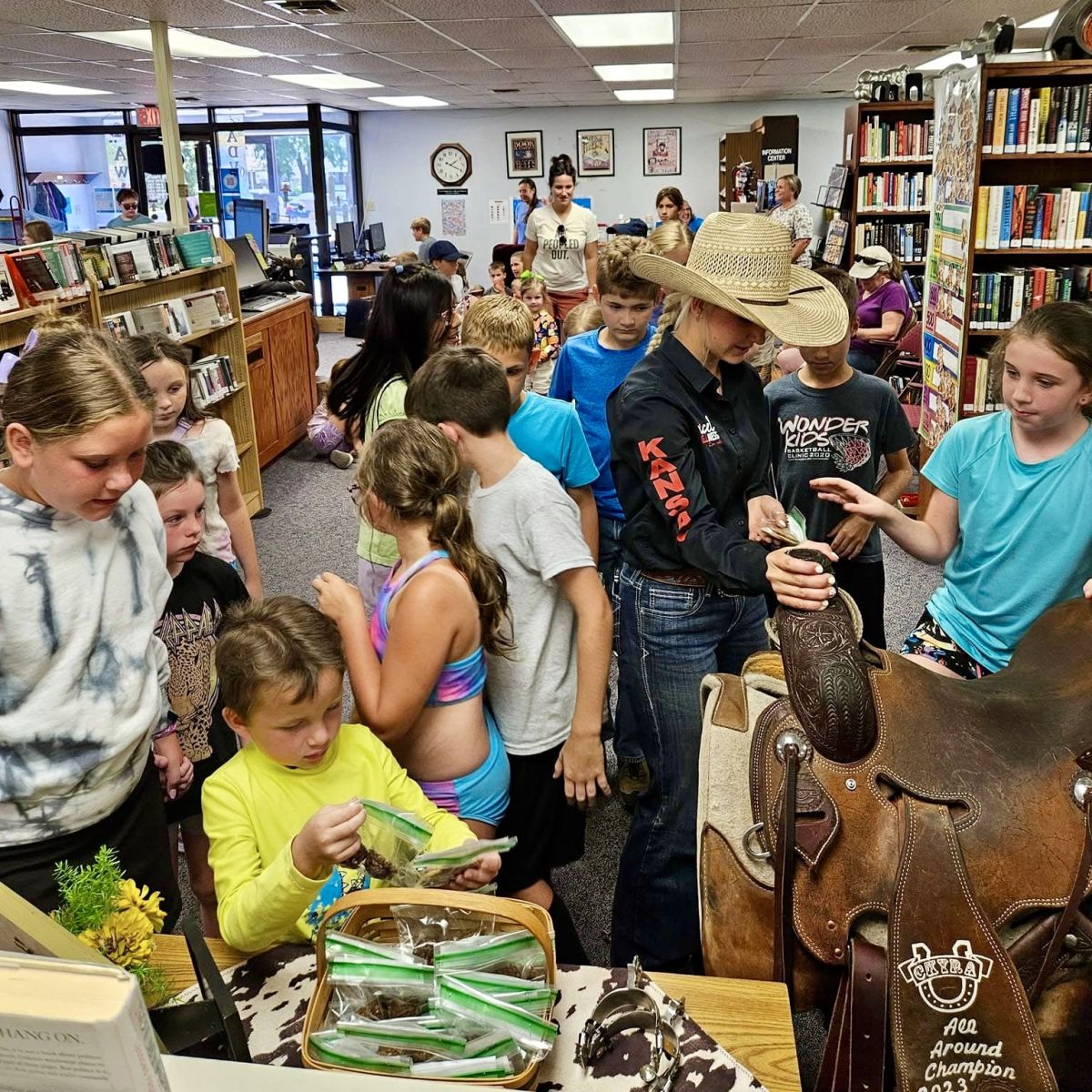 children gathered around a cowgirl and her saddle