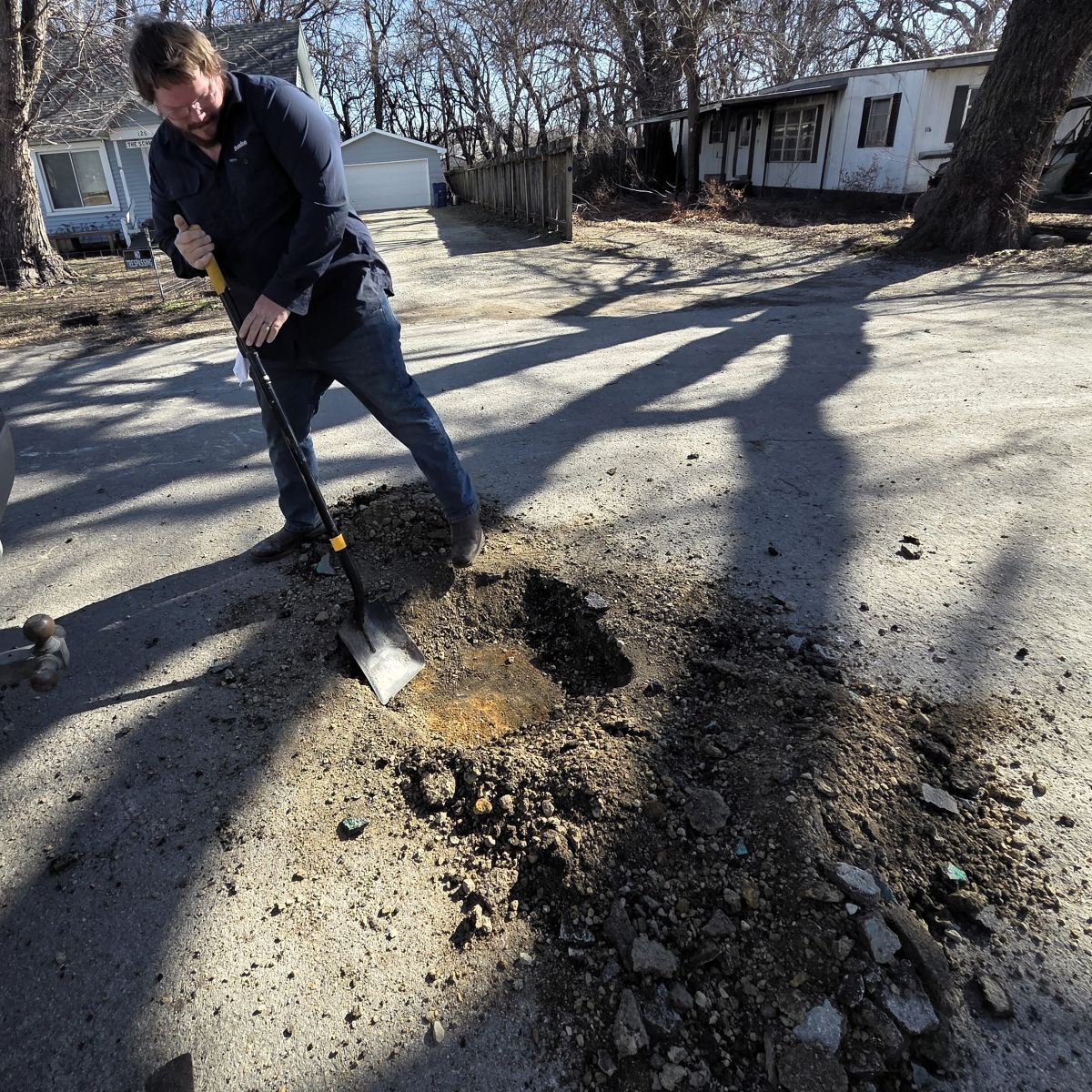 city worker uncovering a buried manhole